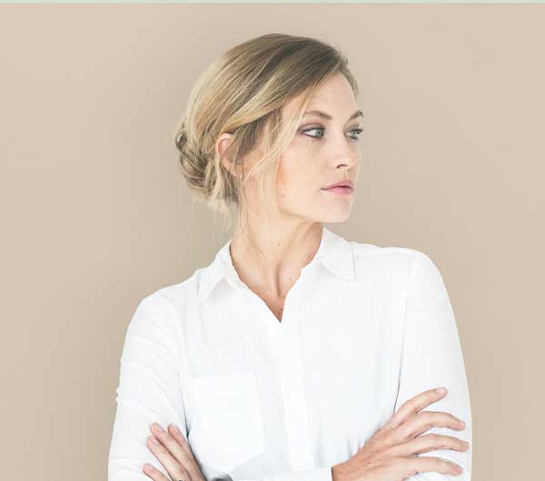 Caucasian woman in white button-up blouse with head facing right