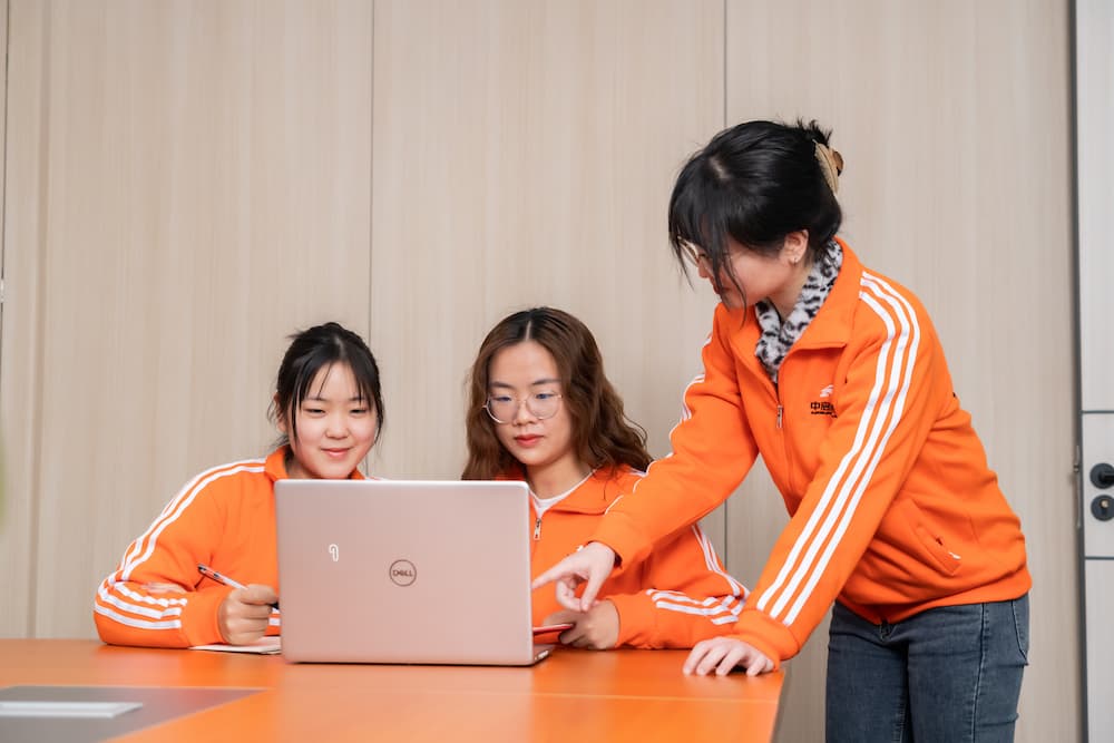 three people looking at a laptop screen