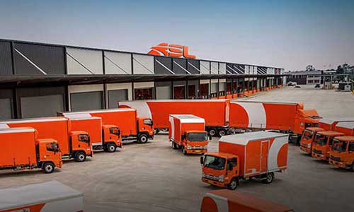 fleet of orange delivery trucks parked on a delivery yard