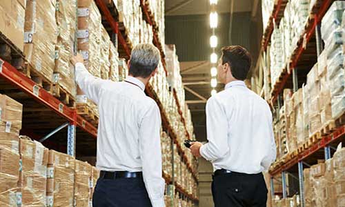 two men in white long-sleeve shirts looking at some boxes