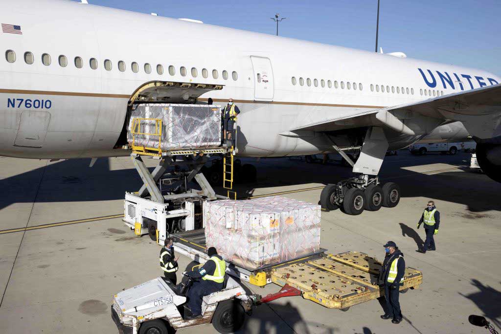 several airport employees loading large cargo in a plane