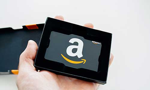 hand holding a mini tablet showing the amazon logo