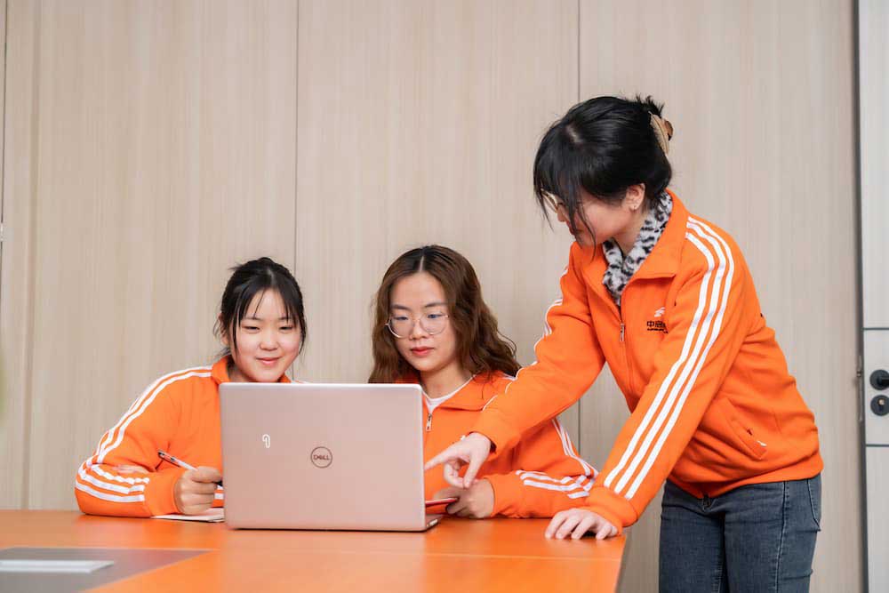 three people in front of a laptop discussing
