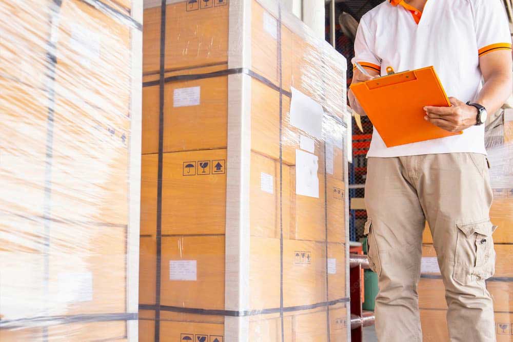 man holding orange clipboard checking cargo before loading