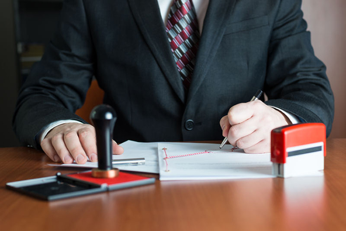 man signing documents, two types of stamps at the table