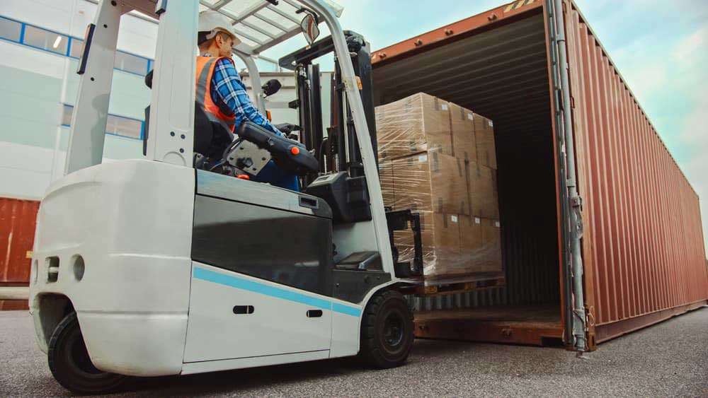 man operating a forklift loading cargo in a container