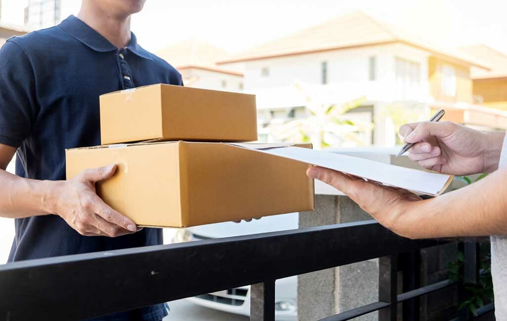 man in blue polo shirt handing two boxes, other person signing papers