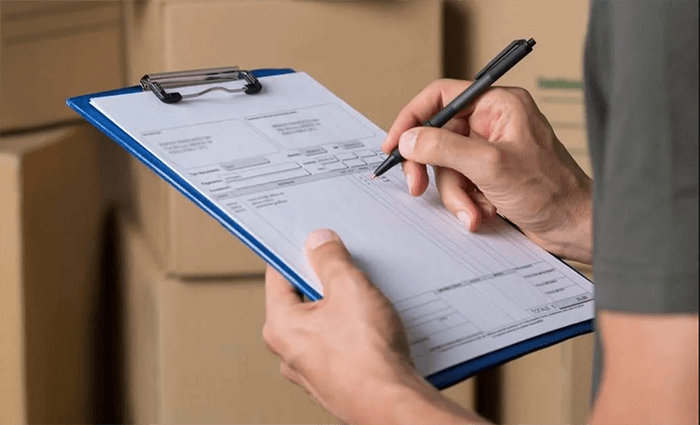 hand holding a clipboard with the other hand writing on a document