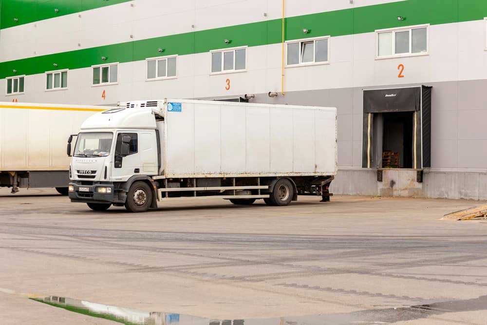 white delivery van leaving a warehouse after loading