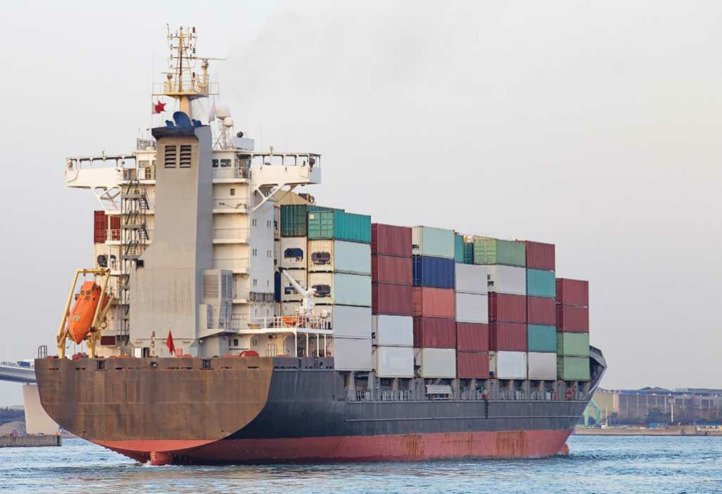 cargo ship with stacks of cargo containers leaving the port