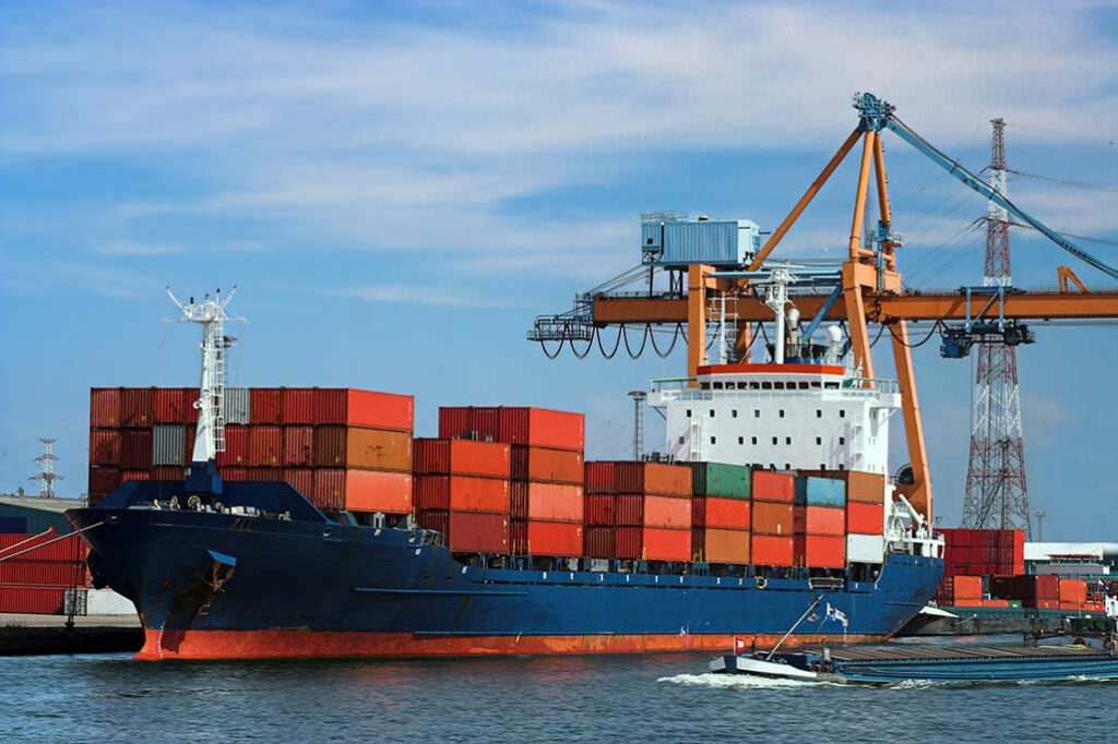 cargo ship loaded with stacks of red and orange storage containers