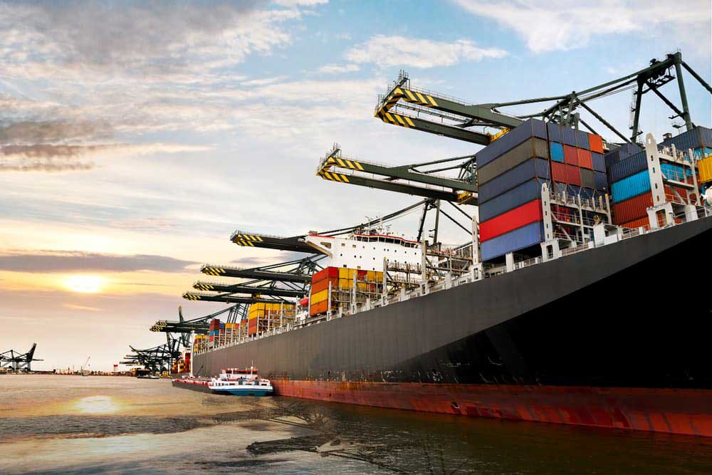 large cargo ship being guided by a couple of tugboats