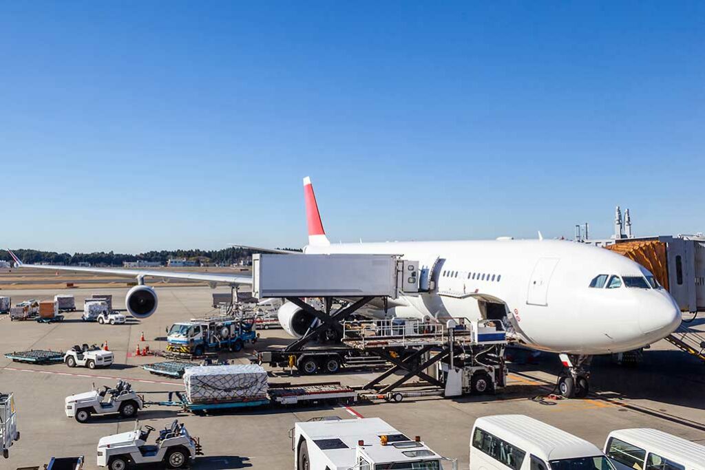 white cargo plane in the process of being loaded with cargo packages